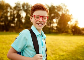 Happy pupil with backpack in park