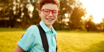 Happy pupil with backpack in park