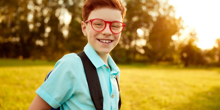 Happy pupil with backpack in park