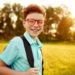 Happy pupil with backpack in park